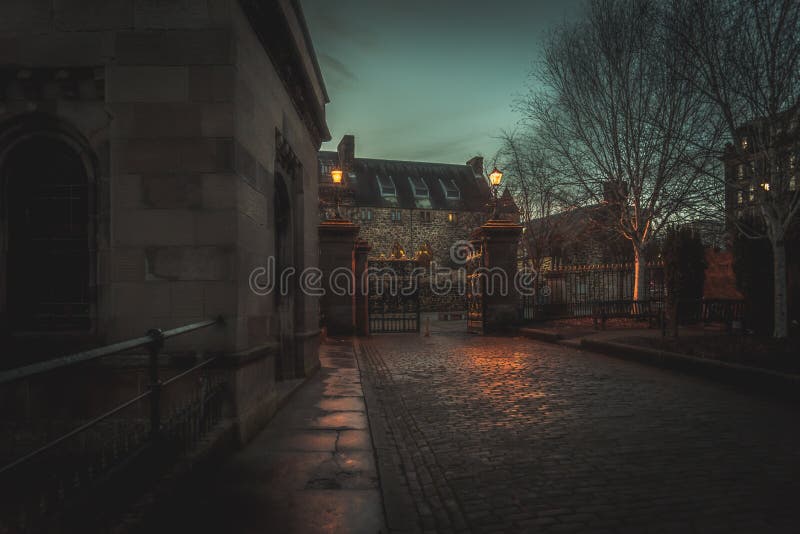 GLASGOW, SCOTLAND, DECEMBER 16, 2018: Creepy cobbled street surrounded by old European style buildings. Illuminated only with weak