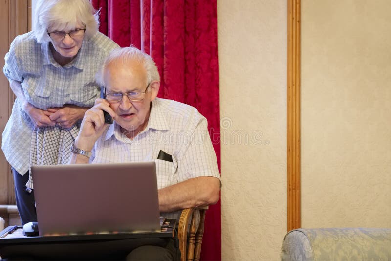 Glasgow, Scotland / UK - 16 agosto 2019:Una coppia di anziani al pc laptop e al telefono per assistenza in seguito al virus della