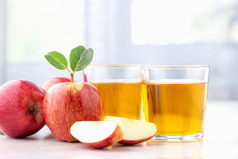 Glass of apple juice and ripe red apples with leaves.