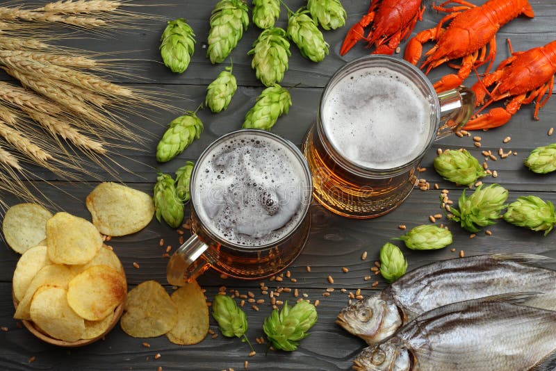 Glass beer with crawfish, dried fish and hop cones on dark wooden background. Beer brewery concept. Beer background. top view