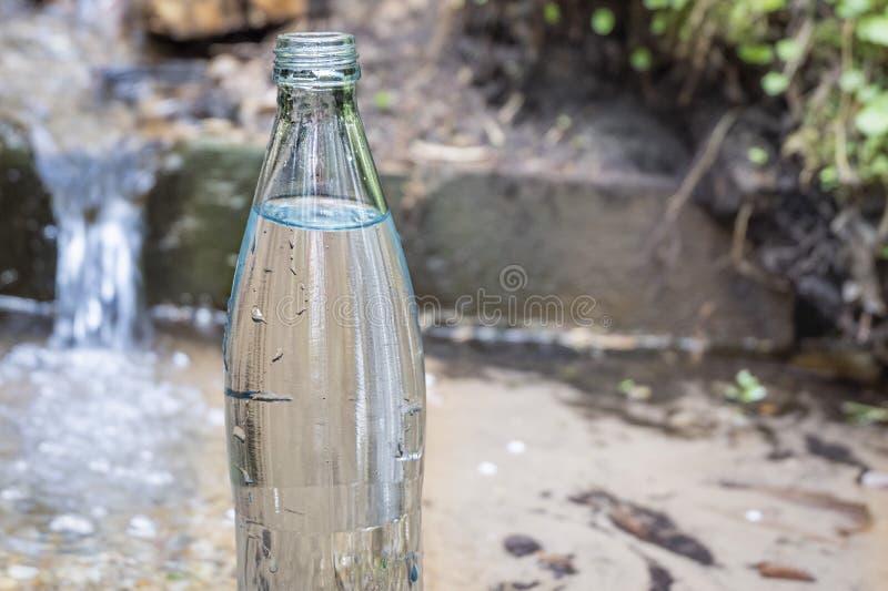 Glass Bottle on the Background of Pure Spring Water Stock Photo Image