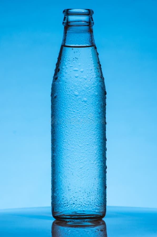 Glass Bottle With Drink In Drop Of Water On Blue Background With