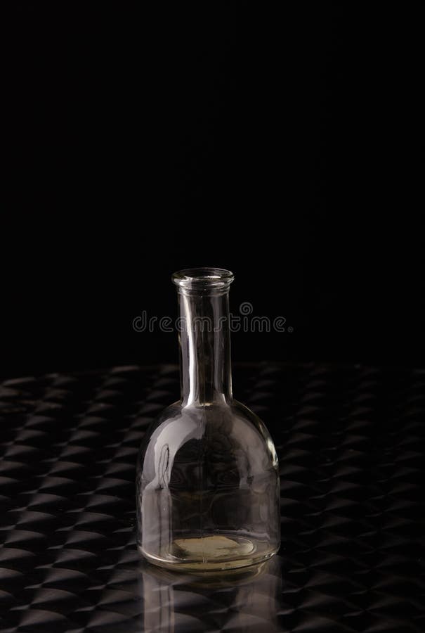 Vuoto bicchiere una bottiglia sul brillante acciaio inossidabile acciaio tavolo contro buio grigio.