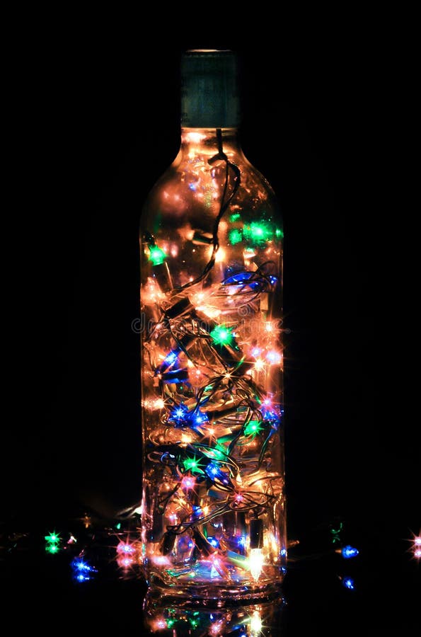 Glass bottle light with christmas yellow orange blue green pink lights over black background stock image Glass bottle light with christmas yellow orange blue green pink lights over black background stock image