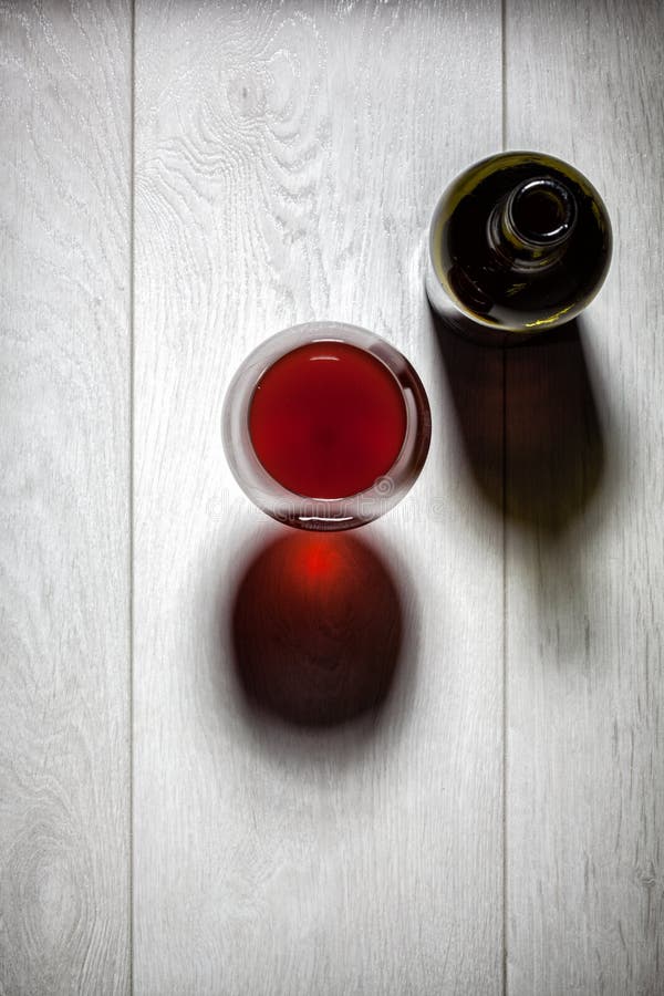 Glass and bottle of red wine with cork on table
