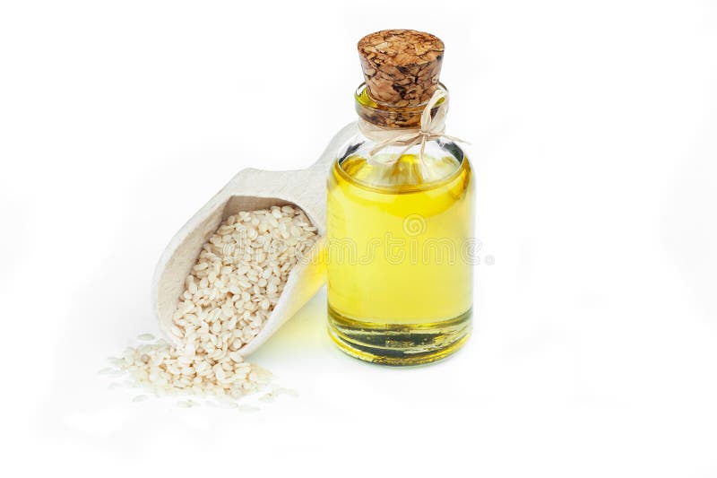 Glass bottle of sesame oil and raw sesame seeds in wooden shovel isolated on white background