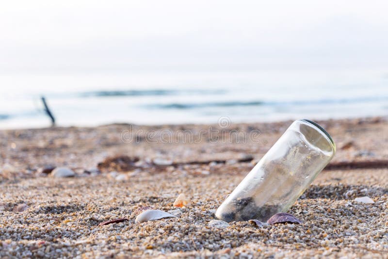 A glass bottles on the beach near the sea. It`s garbage pollutio
