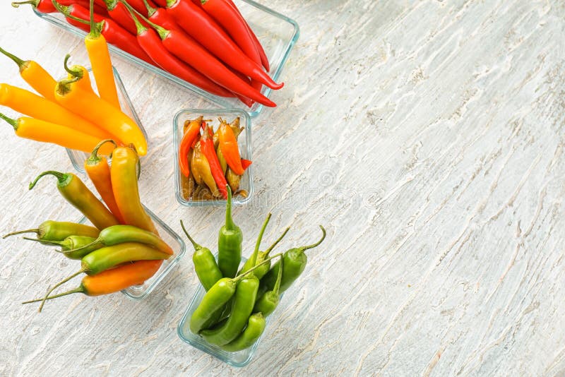 Glass bowls with fresh and canned chili peppers on light background stock photography Glass bowls with fresh and canned chili peppers on light background stock photography