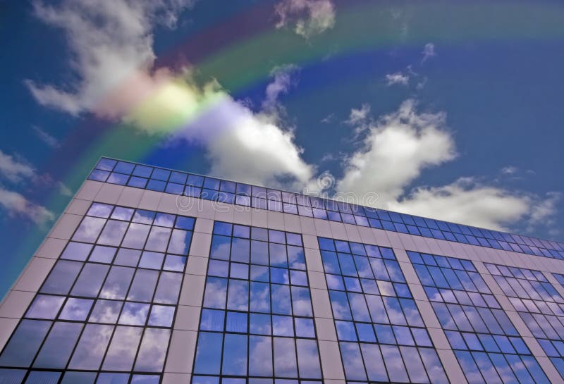 Glass building against a blue sky with rainbow