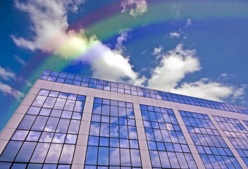 Glass building against a blue sky with rainbow