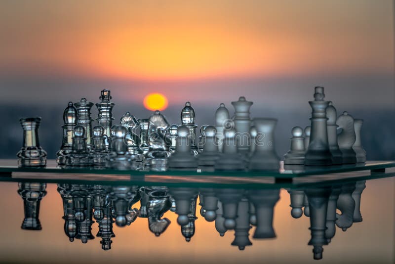 Reflected glass chess pieces with a sunset in the background stock illustration