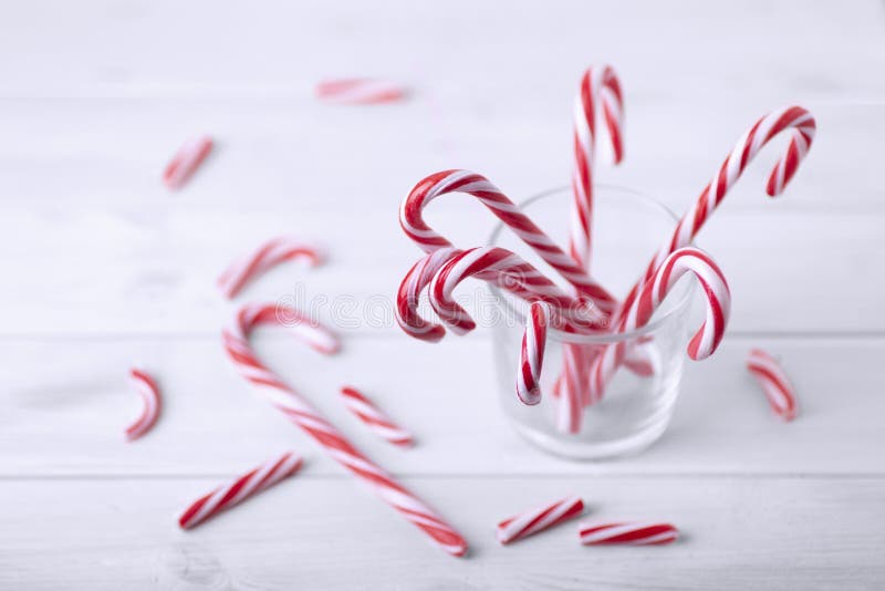 Glass with christmas candy canes on a white wooden table