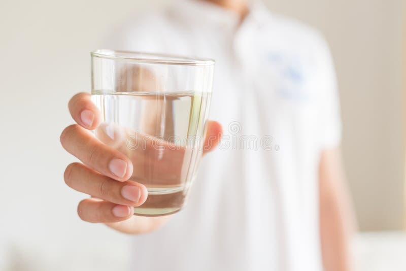 A glass of clean mineral water in man`s hands.