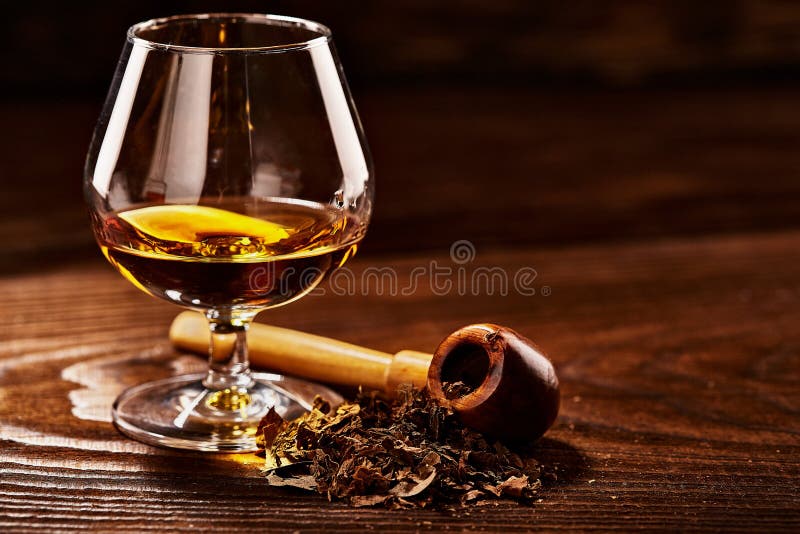 Glass of Cognac and Pipe with Tobacco on Wooden Table Stock Image