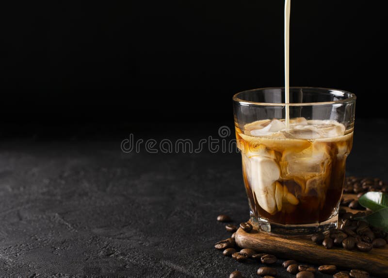 Glass cold brew coffee with ice and milk on black or dark background stock photos