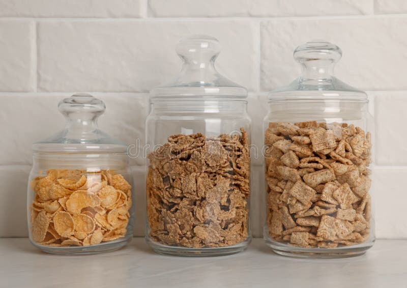 Glass Containers with Different Breakfast Cereals on White Countertop