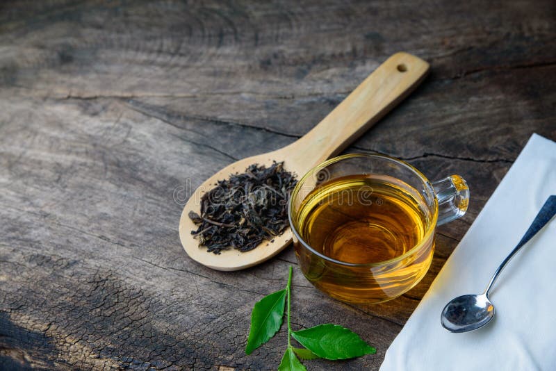 Glass cup of tea and spoons with dried leaves tea