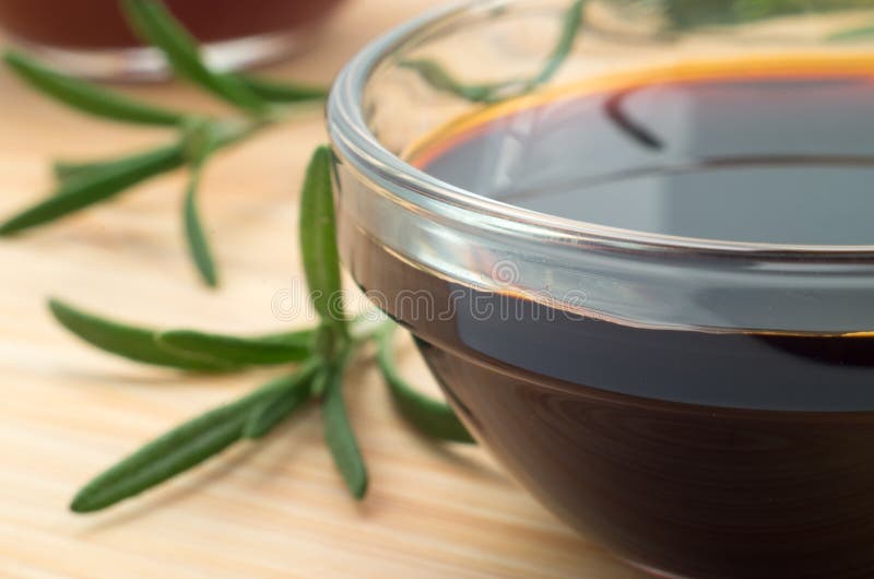 Glass dish with soy sauce and rosemary sprigs