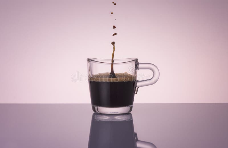 Glass espresso coffee cup  with a drop of coffee falling inside