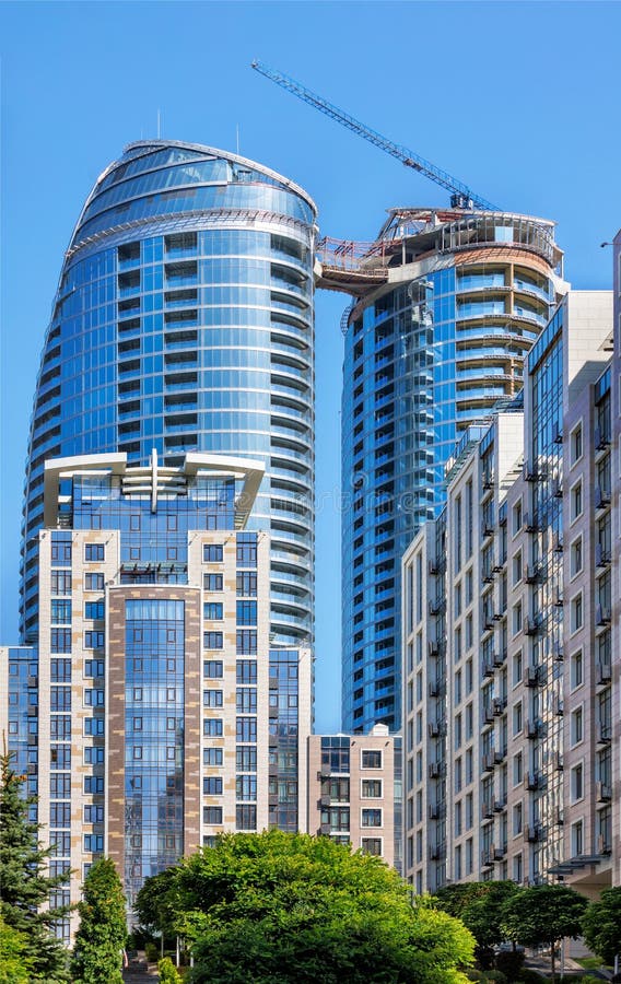 Glass facade of a modern multi-storey residential building under construction against a blue background of the summer sky