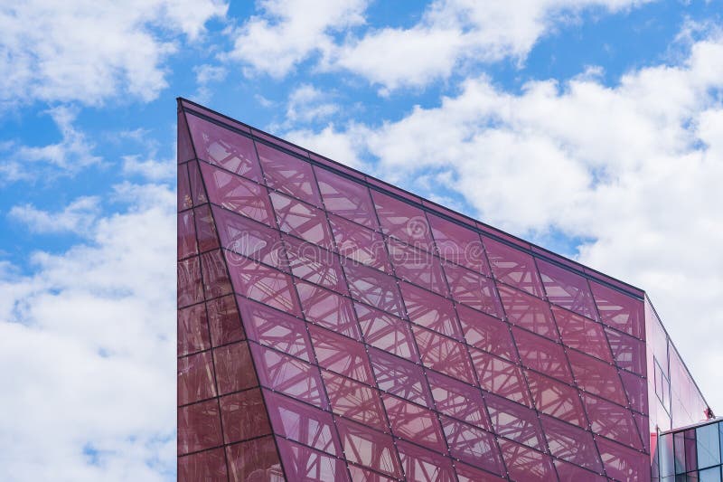 Glass Facade of Violet Tinted Semi-Transparent Glass Building Against Blue Sky with Sunbeams