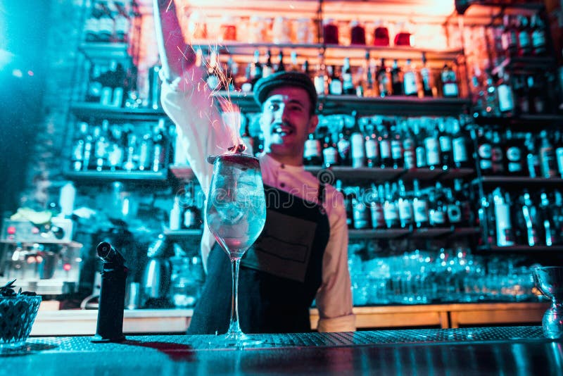 Glass of fiery cocktail on the bar counter against the background of bartenders hands with fire stock photography Glass of fiery cocktail on the bar counter against the background of bartenders hands with fire stock photography