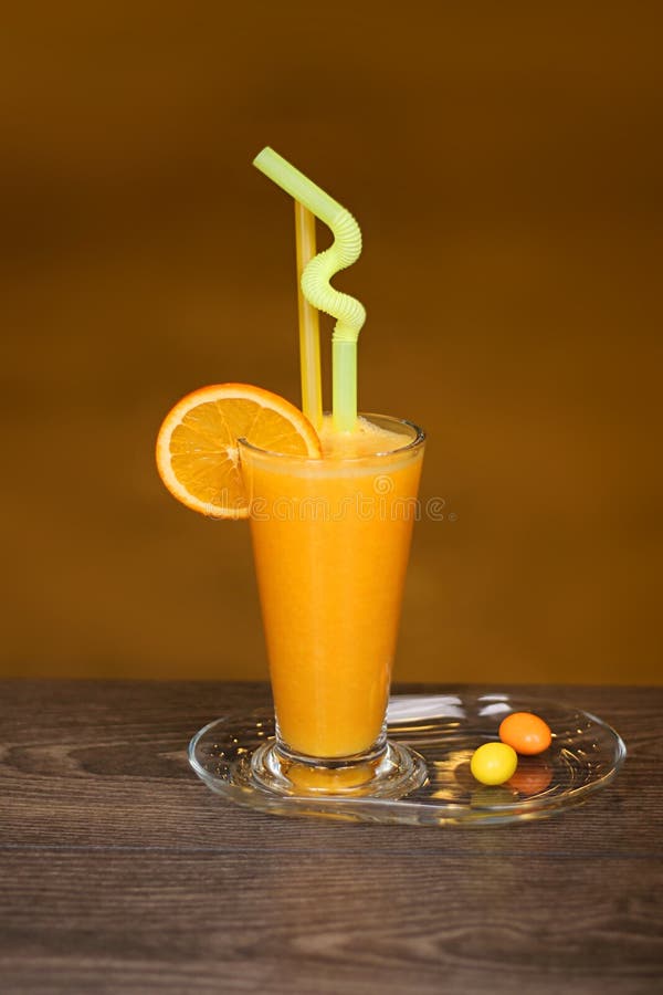 A Glass of Fresh Orange Juice with Straws and Colored Chocolates Stock