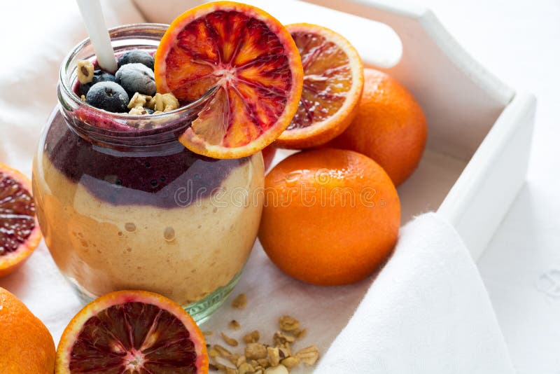 Glass of fresh smoothie with blood orange, blueberry and granola royalty free stock photos