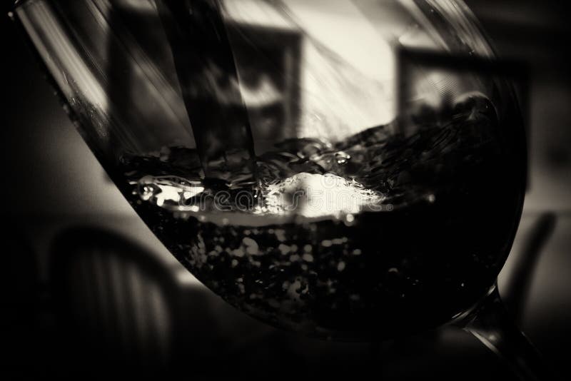 Glass of full bodied red wine being poured stock image