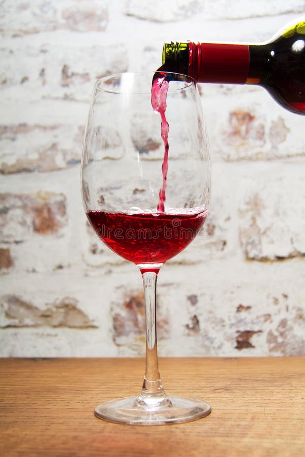 Glass of full bodied red wine being poured royalty free stock photography
