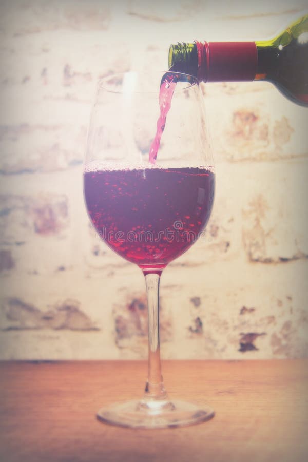 Glass of full bodied red wine being poured stock photo