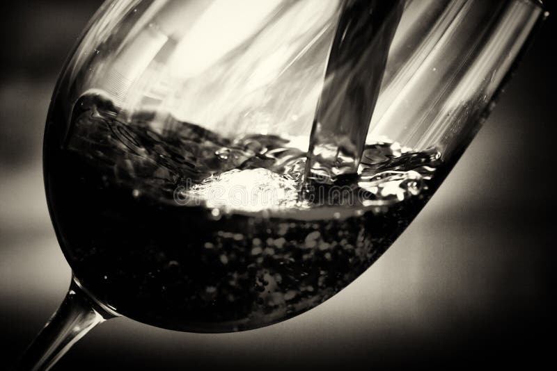 Glass of full bodied red wine being poured royalty free stock photo