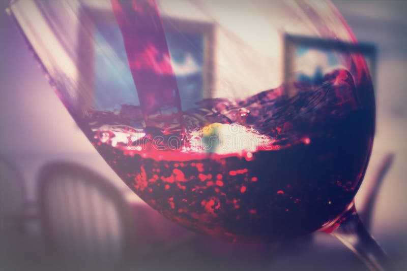 Glass of full bodied red wine being poured royalty free stock image