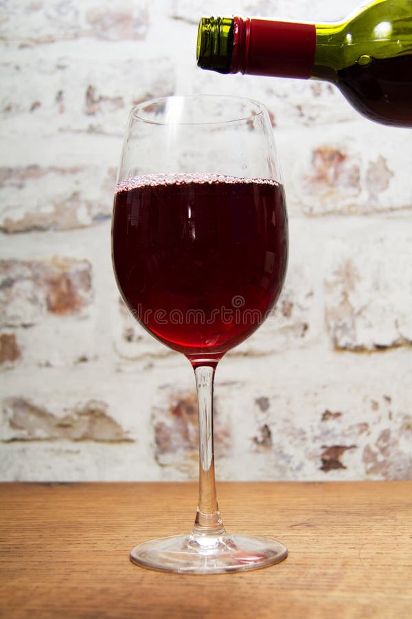 Glass of full bodied red wine being poured royalty free stock photo