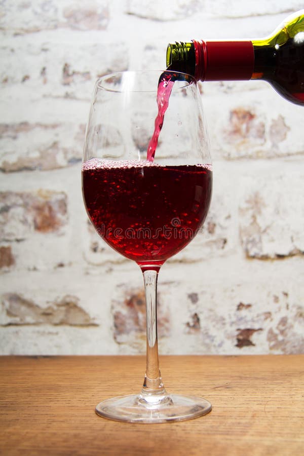 Glass of full bodied red wine being poured. From bottle royalty free stock photo