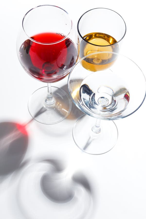 Glass glasses with drinks of different colors on a white background. Top view. The concept of an alcoholic cocktail