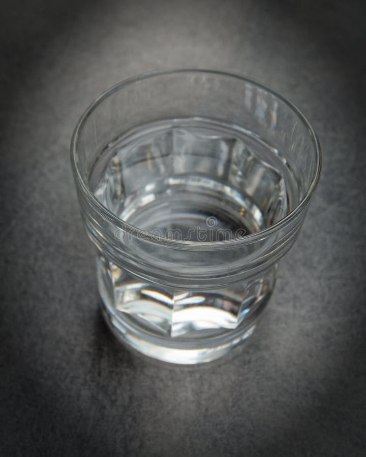 The Glass is Half Full of Water Closeup on a Grey Table with Space for