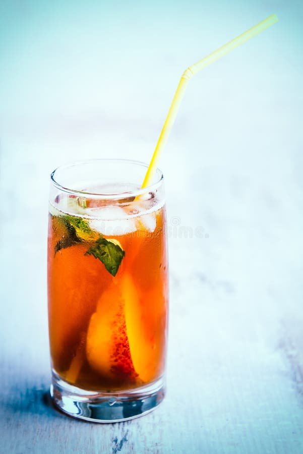 A glass with homemade ice tea, peach flavored. Freshly cut peach slices for arrangement. Light blue wood background. background. stock photo A glass with homemade ice tea, peach flavored. Freshly cut peach slices for arrangement. Light blue wood background. background. stock photo