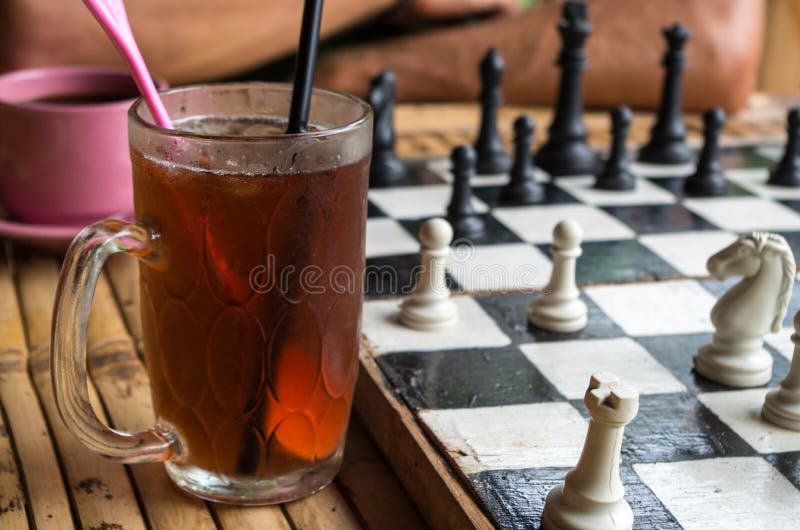 Focused man sipping alcoholic beverage while thinking about next chess move.  Stock Photo by DC_Studio