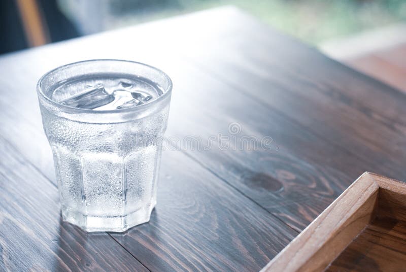 A glass of iced cold water on the wooden table ready to drink for giving a freshness