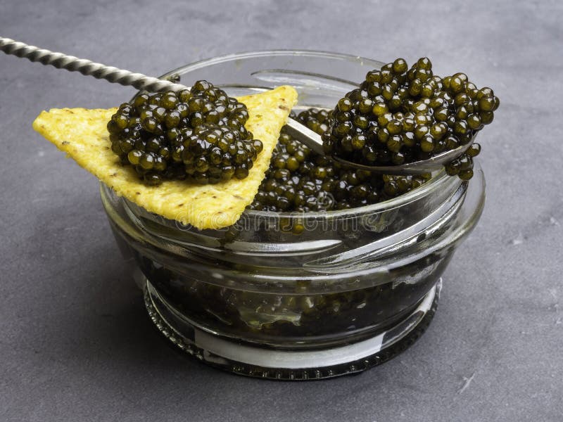 Glass jar with black caviar, and silver vintage spoon, chips. Healthy food. copy space