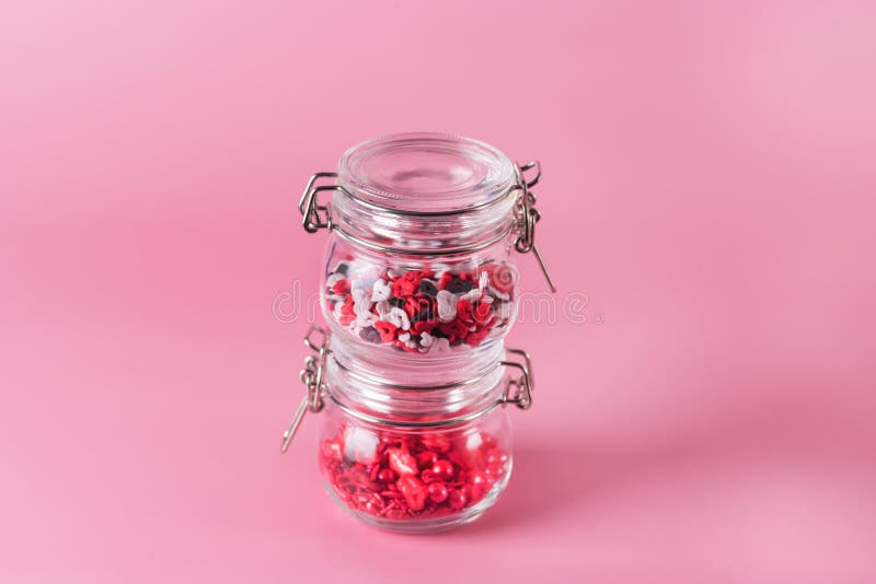 Glass Jar with Candy Sprinkles in Shape of Hearts and Lips on Pink