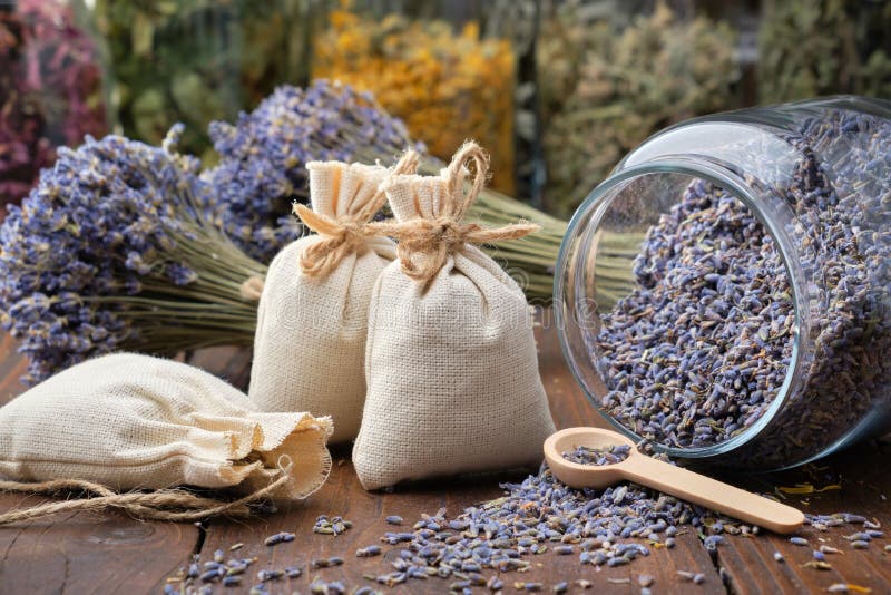 Glass jar of dry lavender flowers, sachets, bunches of dry lavender. Jars of different dry medicinal herbs on background. Alternative medicine