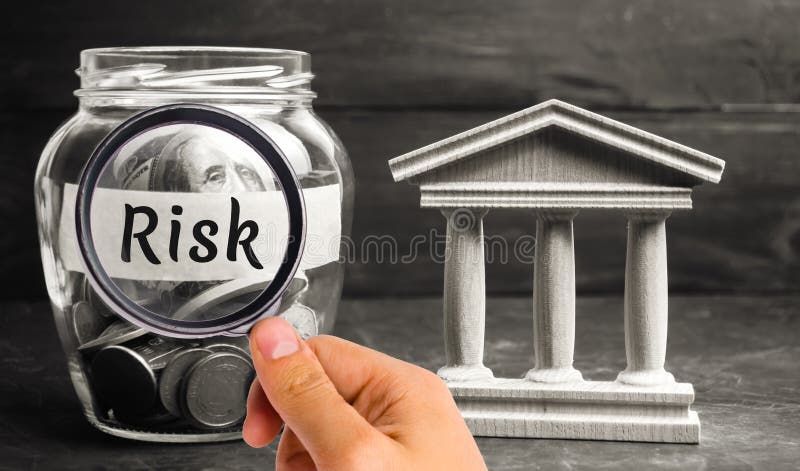A glass jar and the inscription `risk` stands next to a state building. The concept of financial and economic risk. Unreliable inv stock image A glass jar and the inscription `risk` stands next to a state building. The concept of financial and economic risk. Unreliable inv stock image