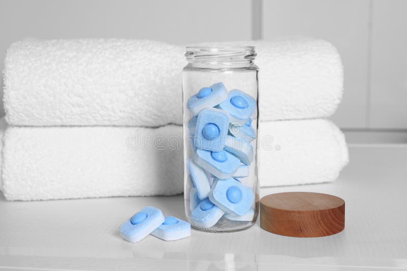 Glass jar with water softener tablets on washing machine in bathroom