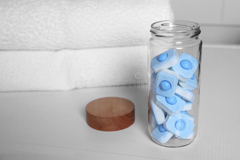 Glass Jar with Water Softener Tablets on Washing Machine in Bathroom, Space for Text Stock Photo