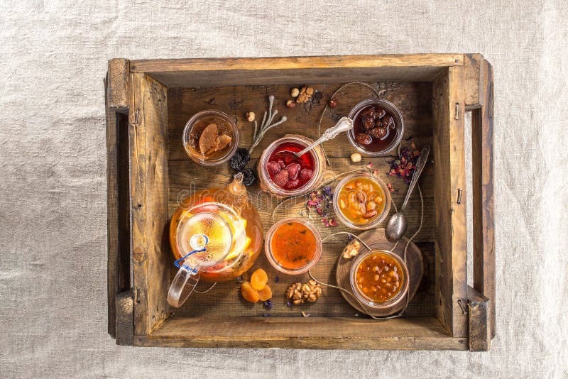 Glass Jars with Different Kinds of Jam and Teapot in Wooden Box Stock