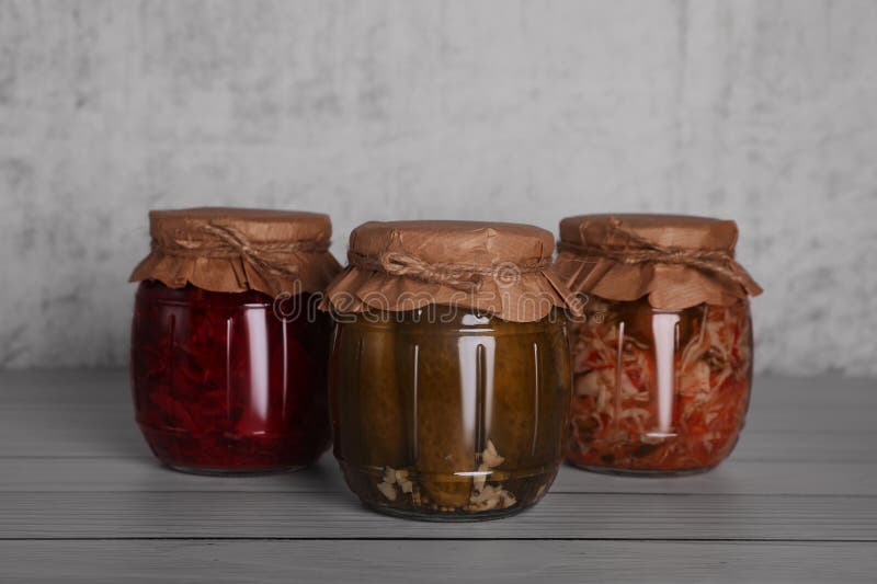 Glass Jars with Different Preserved Vegetables on Wooden Table Stock