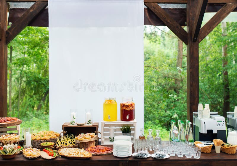 Glass jars of lemonade on wedding candy bar. Catering. Drinks on wedding party. Summer wedding in the forest.