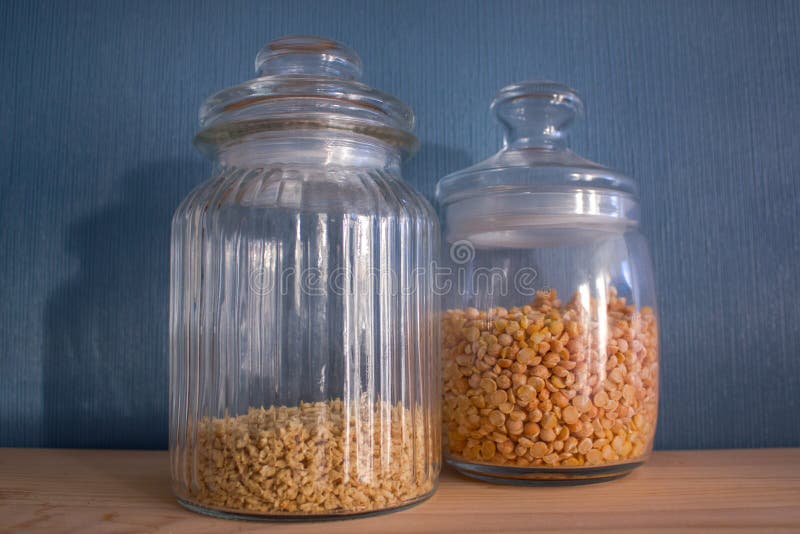 Glass jars with minced meat and peas on a wooden shelf. Beautifully organized storage in the kitchen